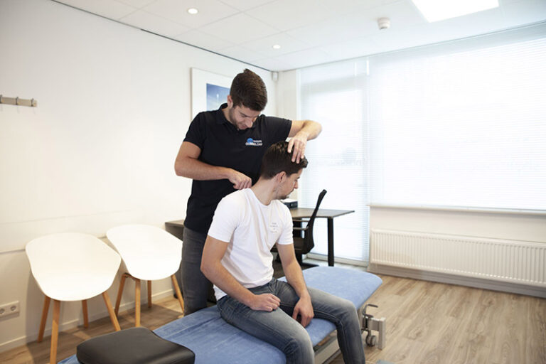 Manueel therapeut Reno Bosman in zijn Fysio Dubbeldam outft helpt patiënt Peter in het witte shirt zijn klachten door middel van manuele therapie in Sterrenburg