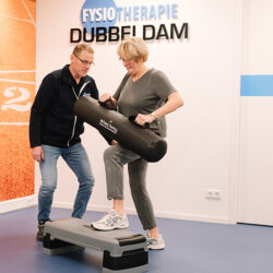 Vrouw in sportkleding traint bij de fysiotherapeut in de oefenzaal voor fysiotherapie bij knieklachten en krijgt knie-revalidatie