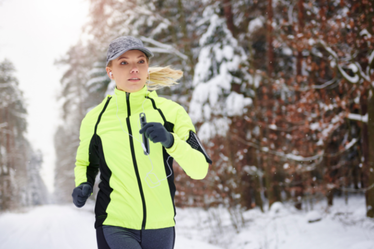 Vrouw loopt hard in een geel hesje buiten in de kou