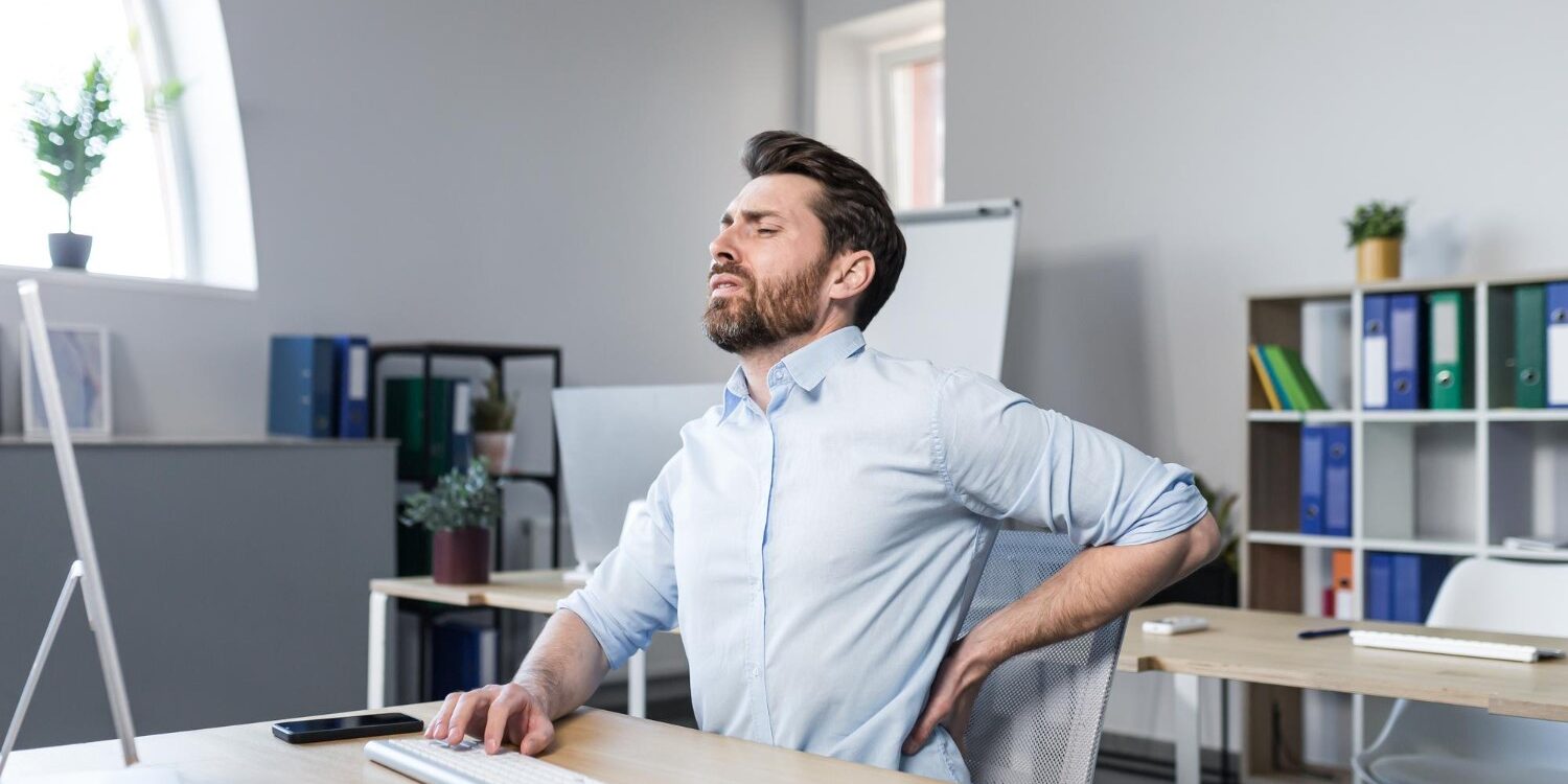 Rugpijn kantoorbaan Man heeft last van rugpijn tijdens het werken