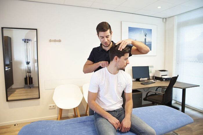 Nekpijn Man heeft nekpijn en wordt geholpen door de fysiotherapeut met fysiotherapie Zwijndrecht