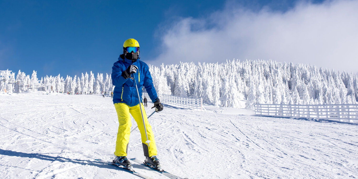 Skiduim Een persoon met ski kleding en een skiduim staat op ski's in de sneeuw.