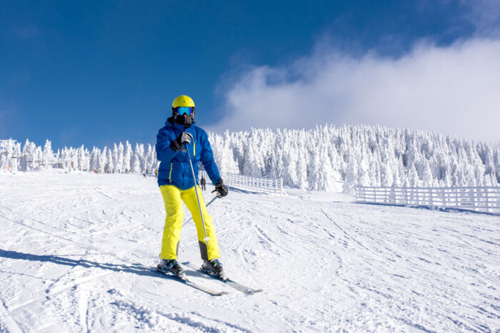 Skiduim Een persoon met ski kleding en een skiduim staat op ski's in de sneeuw.