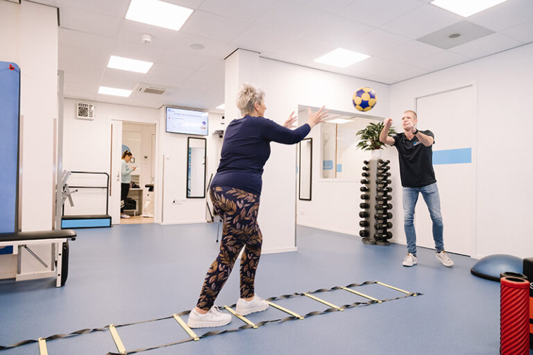 Vrouw in haar pensioen blijft fit door te sporten tijdens fysiotherapie