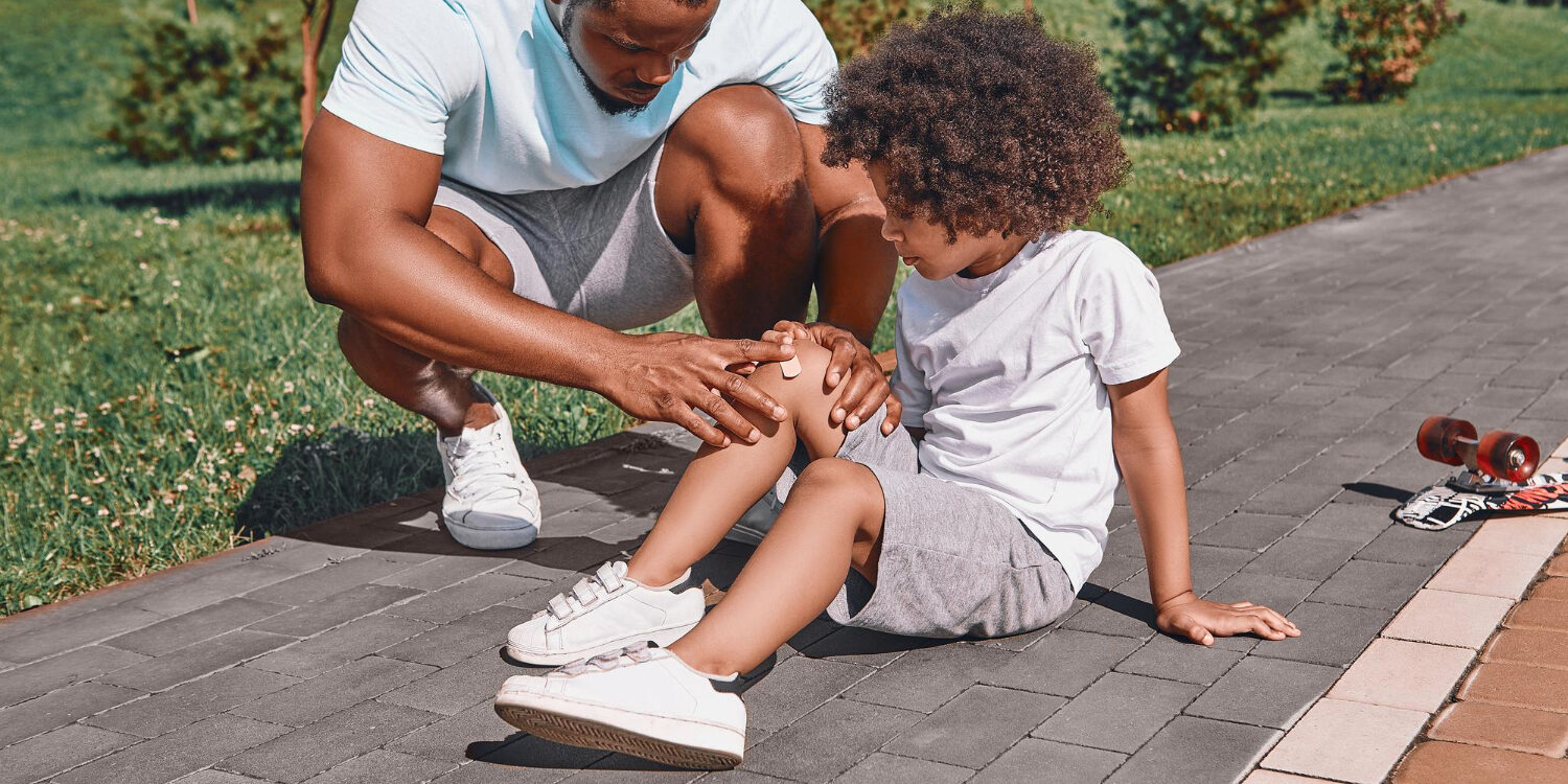 Jongentje heeft een blessure, zijn vader helpt hem