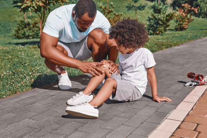 Leeftijd invloed op blessures Jongentje heeft een blessure, zijn vader helpt hem