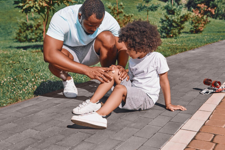 Jongentje heeft een blessure, zijn vader helpt hem