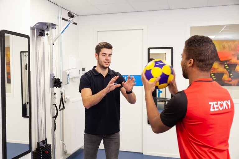 Een fysiotherapeut die een jongen instructies geeft met een bal terwijl hij schuldig is aan te veel sporten