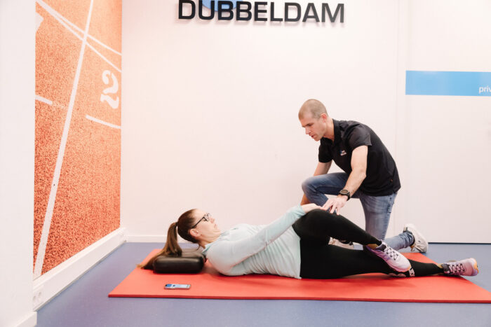 Vrouw krijgt hulp van de fysiotherapeut in de oefenzaal met knakkende knieën door middel van knie-revalidatie