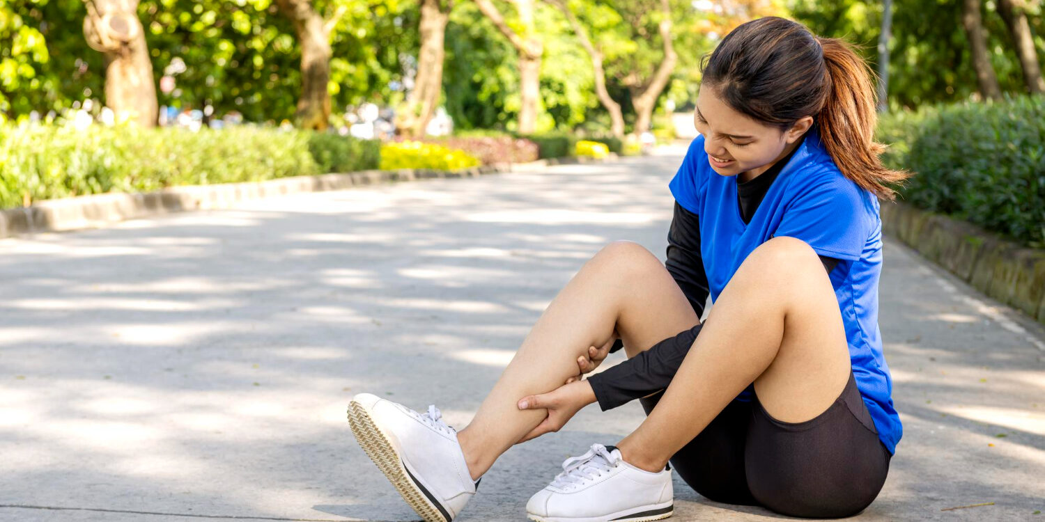 hardloopblessures Vrouw zit buiten op de grond en heeft hardloopblessures opgelopen