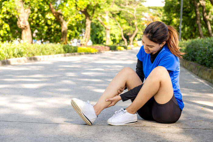 hardloopblessures Vrouw zit buiten op de grond en heeft hardloopblessures opgelopen