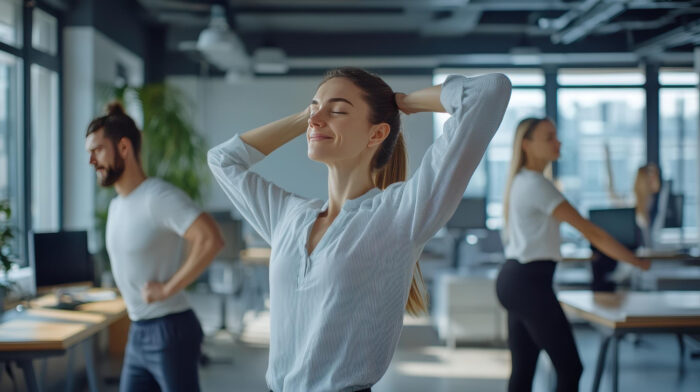 Een vrouw doet oefeningen op werk om nek- en schouderklachten te voorkomen.