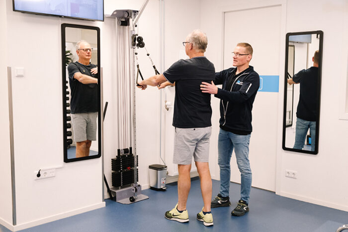 Man wordt geholpen door een fysiotherapeut in de oefenzaal aan zijn stress en rugklachten