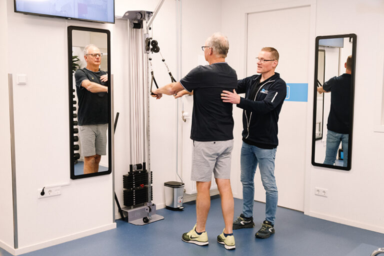 Man wordt geholpen door een fysiotherapeut in de oefenzaal aan zijn stress en rugklachten