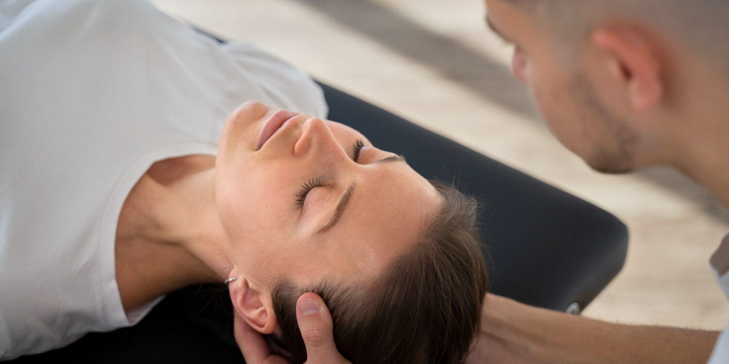 Vrouwelijke patiënt krijgt een behandeling fysiotherapie bij hoofdpijn in Papendrecht van een fysiotherapeut op de behandelbank.