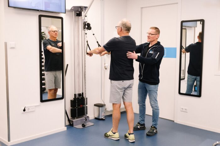 blessures in de sportschool Man voorkomt blessures in de sportschool onder begeleiding van de fysiotherapeut in de oefenzaal.