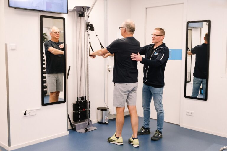Man voorkomt blessures in de sportschool onder begeleiding van de fysiotherapeut in de oefenzaal.