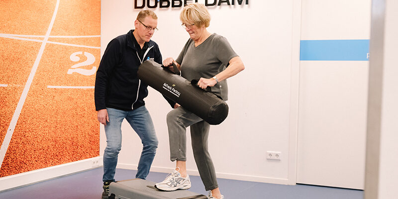 Fysiotherapeut helpt vrouw met haar achillespeesklachten na het sporten.